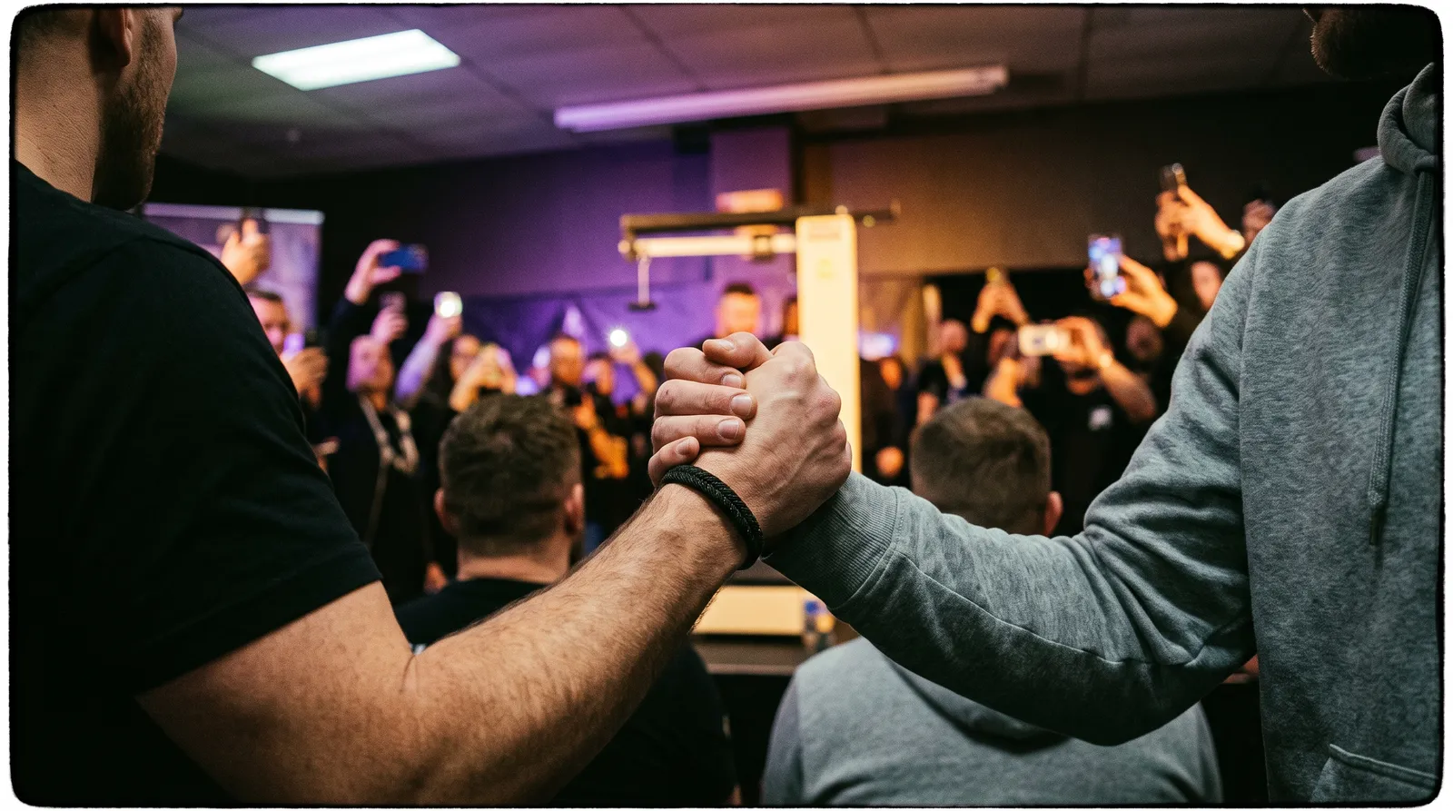 Two men shaking hands in a crowd at a UFC ceremonial weigh-in, with the stage lights blurred behind them