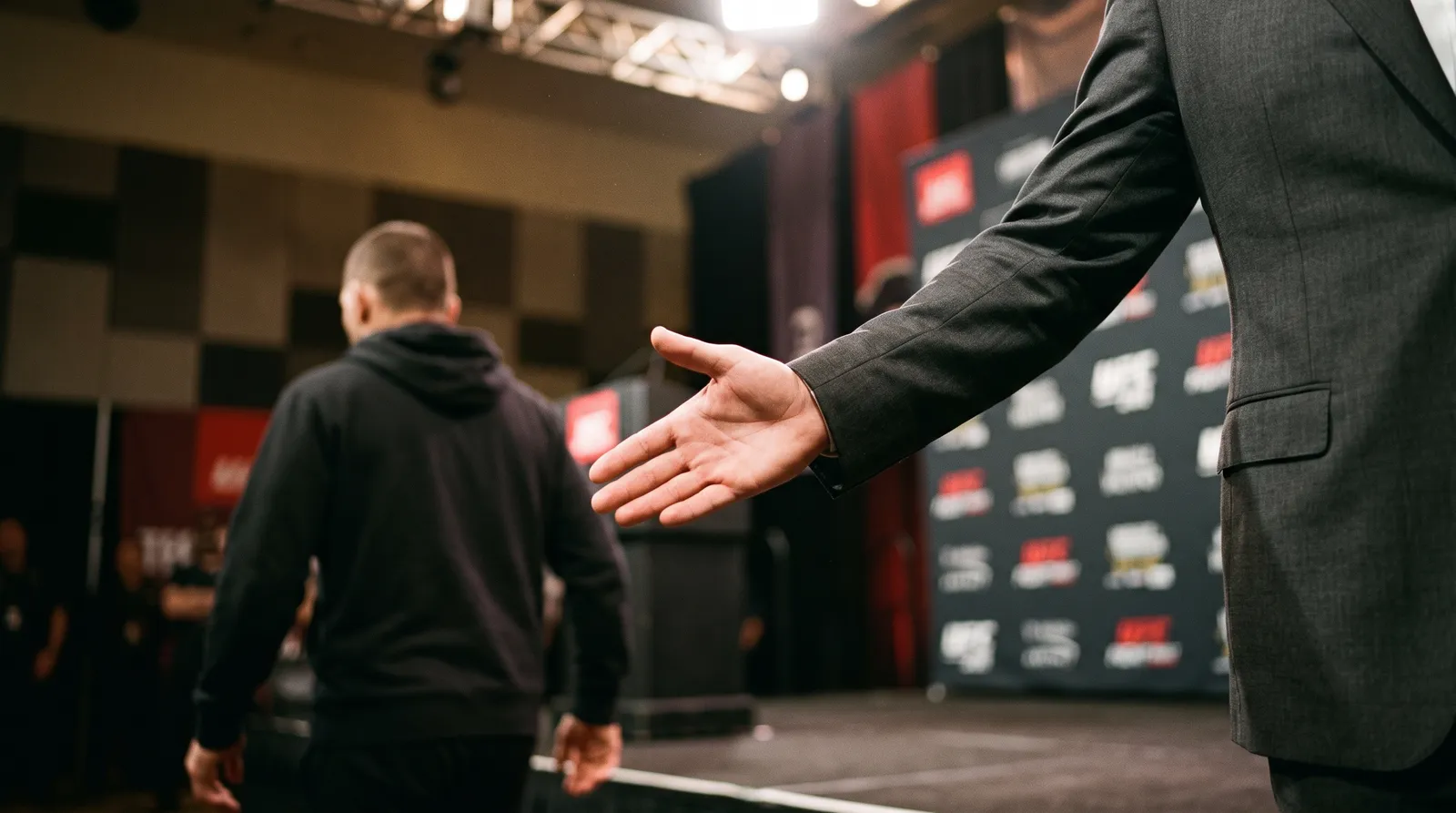An outstretched hand left hanging on a fight-week stage under bright spotlights