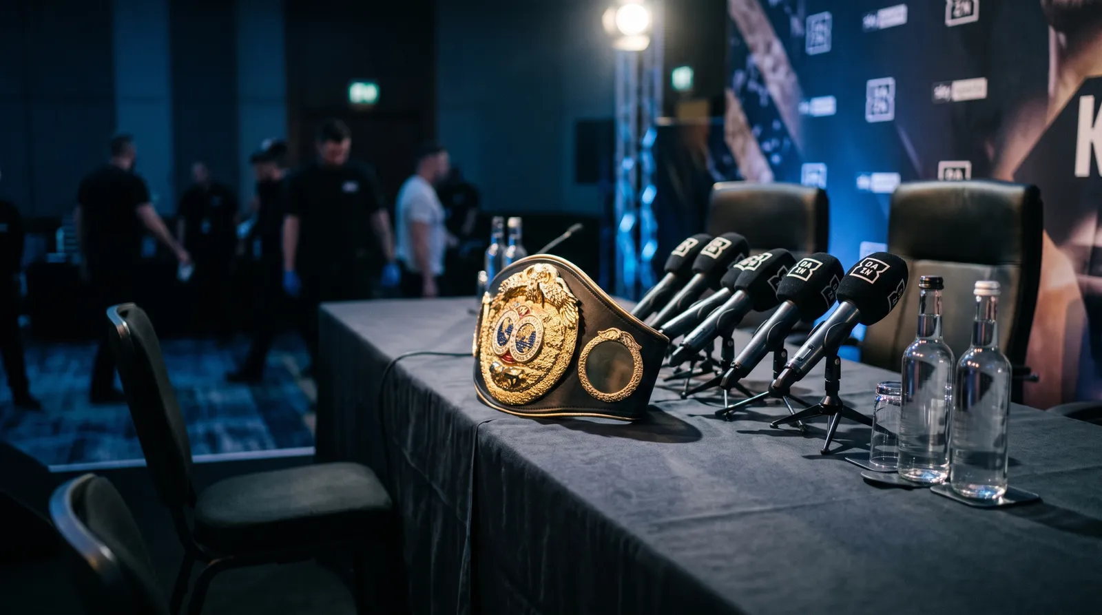 Press conference table with microphones and a championship belt before a lightweight title fight