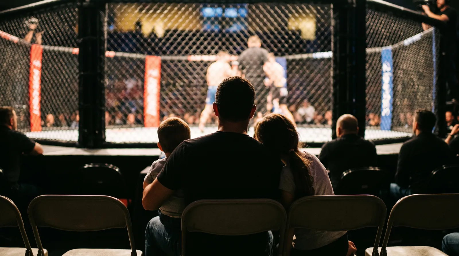 A father with his children seen from behind in cageside seats facing a lit octagon